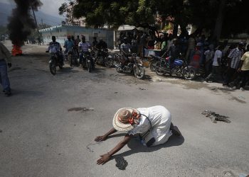A churchgoer drops to the ground and prays in the street near burning tires lit by protesters, during a march called by religious leaders in Port-au-Prince, Haiti, on Oct. 22, 2019. Anger over corruption, inflation and scarcity of basic goods including fuel led to weeks of demonstrations that paralyzed the country as despairing citizens called for the resignation of President Jovenel Moise.(AP Photo/Rebecca Blackwell)